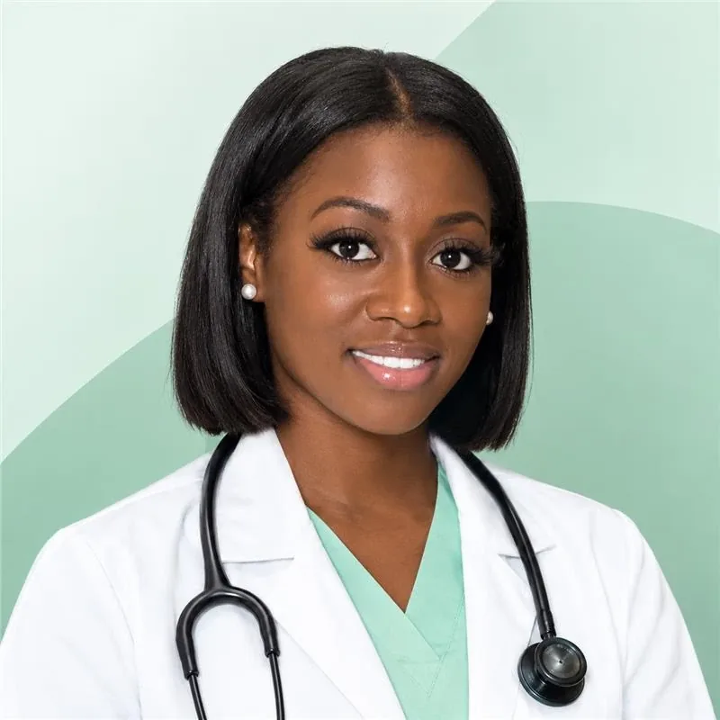 A smiling woman with a dark bob in a white coat and mint scrubs, a stethoscope around her neck